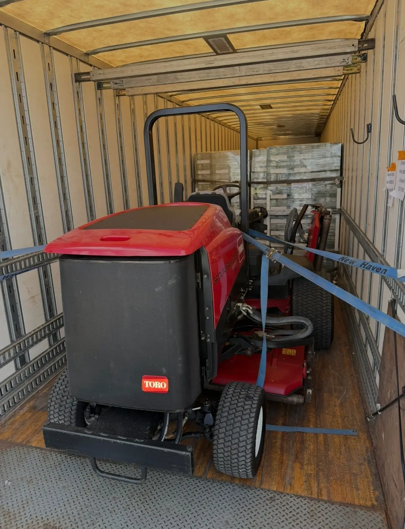 small trucking carrying a single red mower